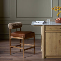Fern Bar + Counter Stool in taupe shearling with a warm leather seat in a modern kitchen.