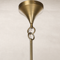 Aged brass iron chandelier featuring a sleek conical shade and decorative linkage.