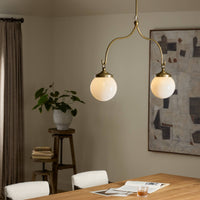 Aged brass iron chandelier with two globes, elegantly illuminating a modern dining space.