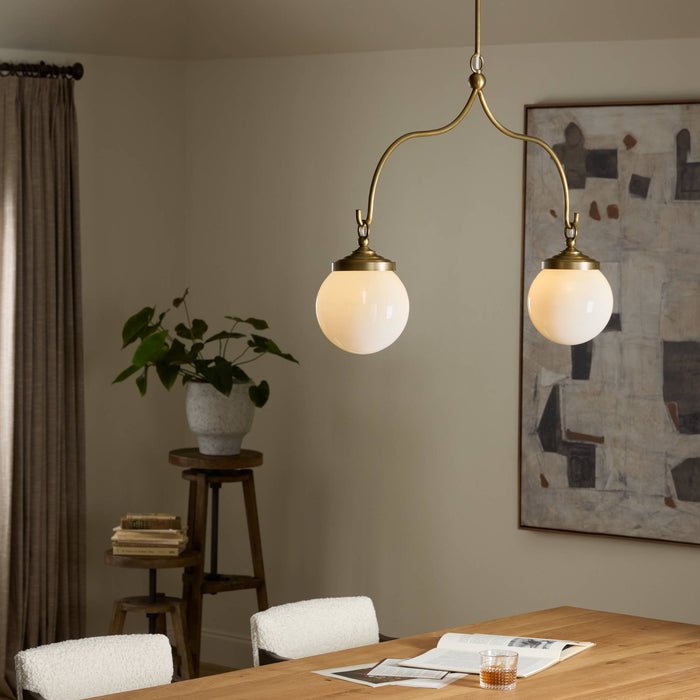 Aged brass iron chandelier with two globes, elegantly illuminating a modern dining space.