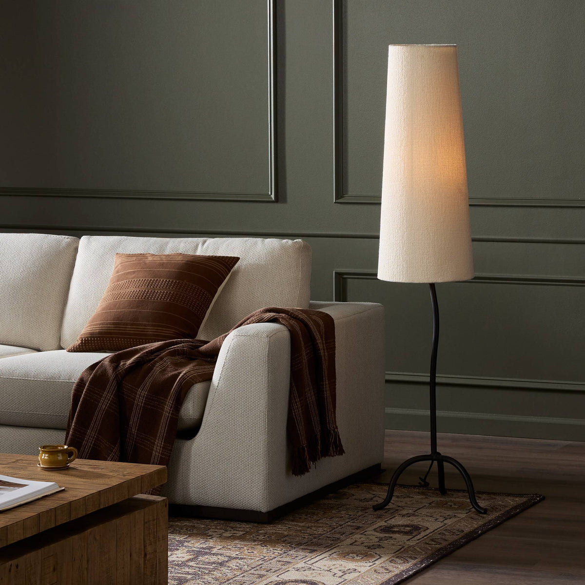 Elegant black wrought iron floor lamp with tapered shade illuminating a stylish living room.