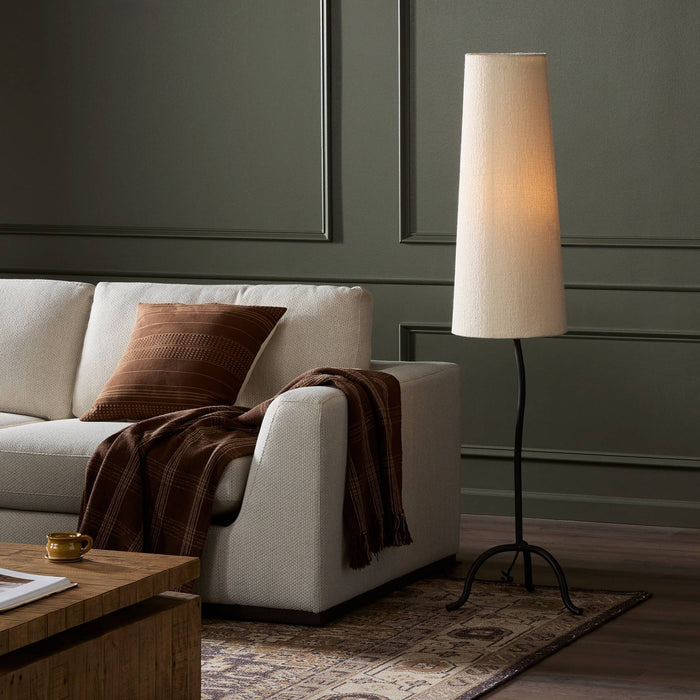 Elegant black wrought iron floor lamp with tapered shade illuminating a stylish living room.