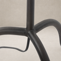 Close-up of a black wrought iron floor lamp's base with curved legs.