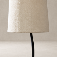 Black wrought iron floor lamp with textured cream fabric shade.