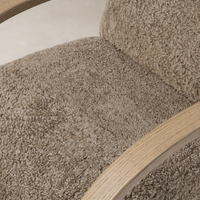 Close-up of the Roan Chair's taupe shearling upholstery and smooth wooden armrest.