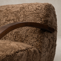 Close-up of the Roan Chair in amber shearling showcasing its soft texture and wooden armrest.