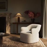 Amira Swivel Chair in soft natural sheepskin, featuring a curved, cozy design.