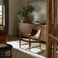 Side angle of the Marcella Accent Chair showcasing its leather seat and woven design in a cozy living room setting.
