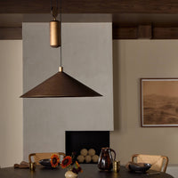 Burnished brass aluminum pendant light hanging above a styled dining table.