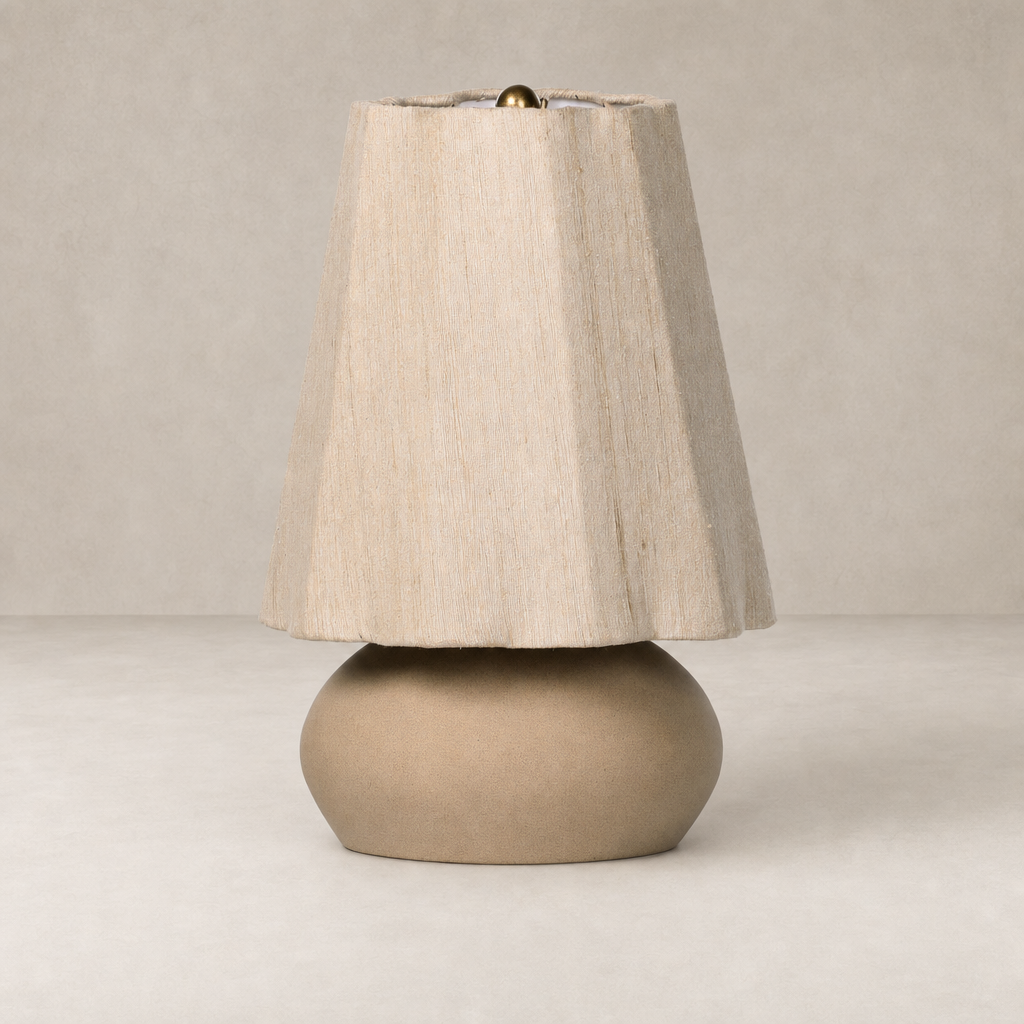 Tan speckled ceramic table lamp with a textured fabric shade and brass finial.