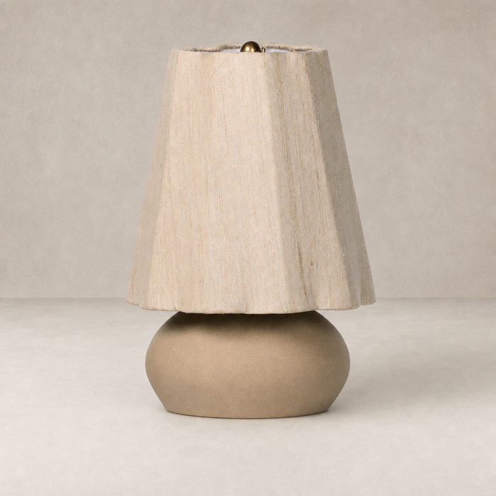 Tan speckled ceramic table lamp with a textured fabric shade and brass finial.