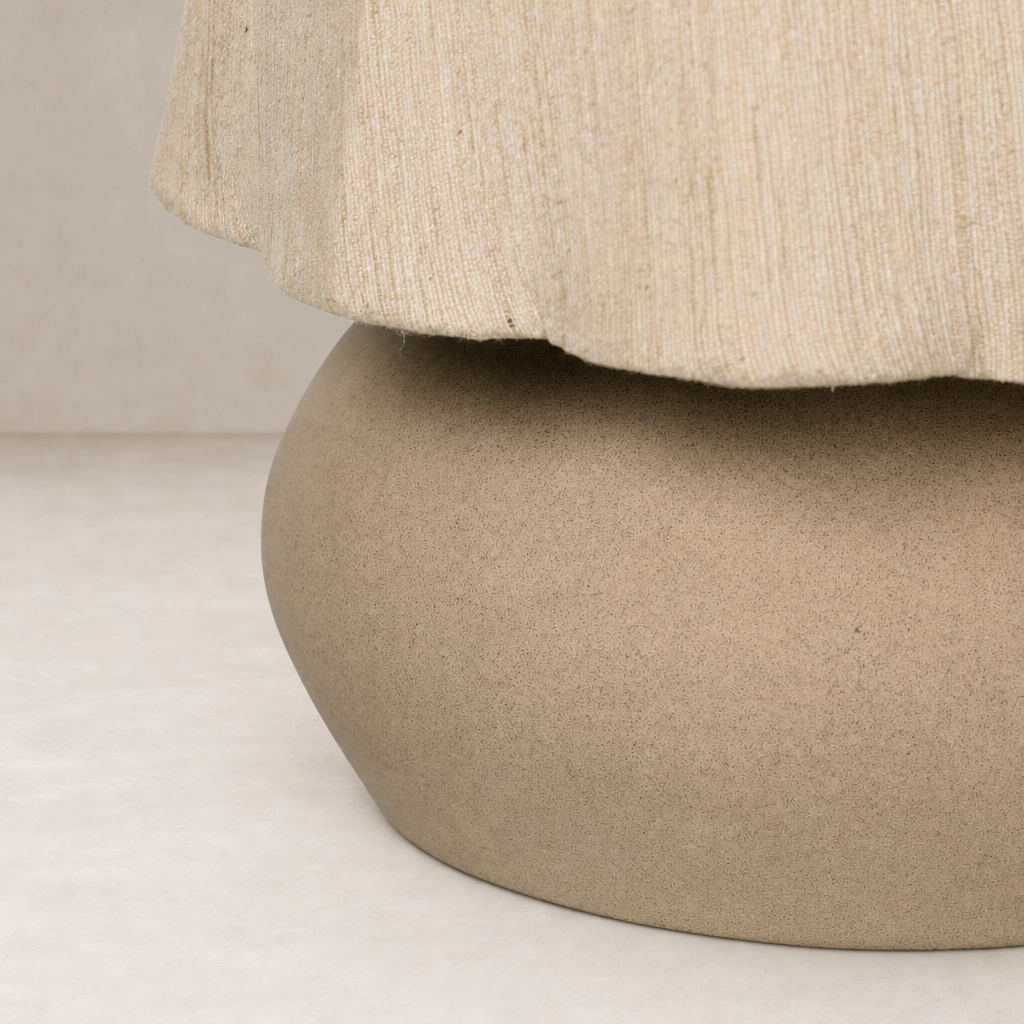 Tan speckled ceramic table lamp with soft fabric shade and rounded base.