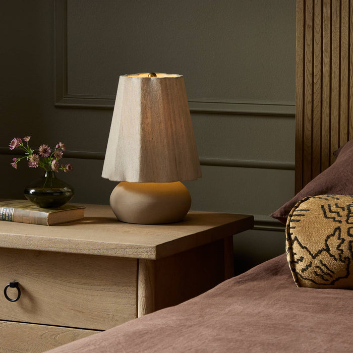 Tan speckled ceramic table lamp with a textured shade on a bedside table.