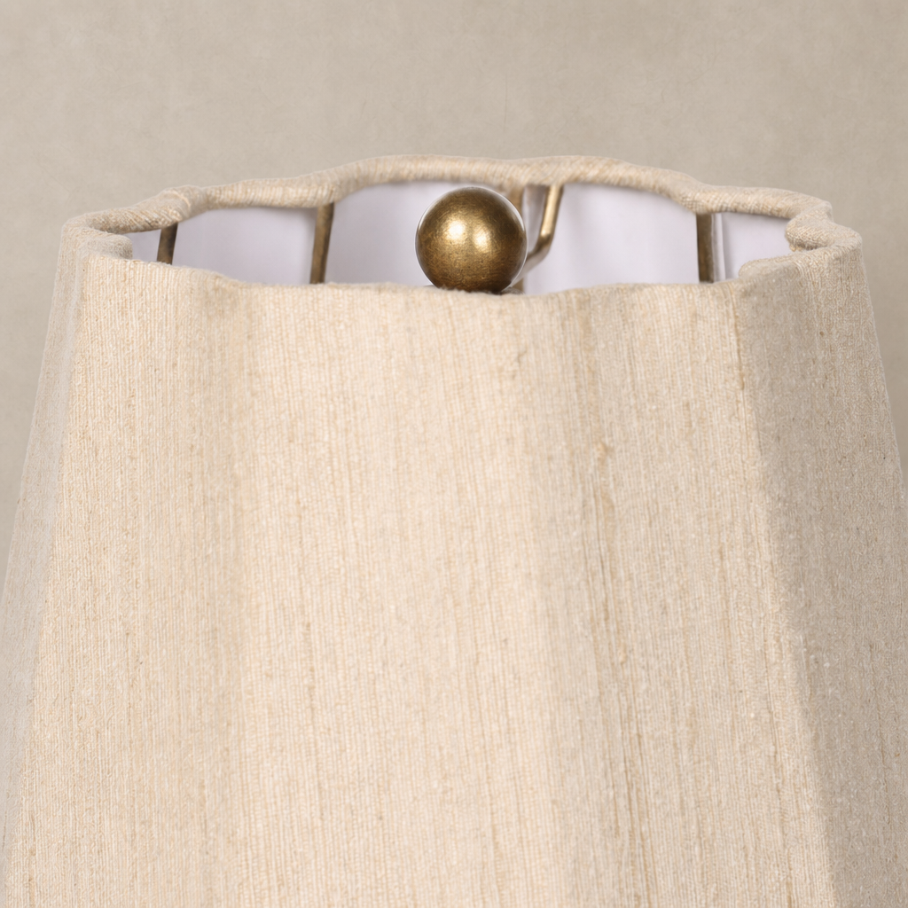 Tan speckled ceramic table lamp showing a textured fabric shade with a decorative finial.