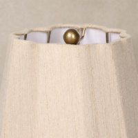 Tan speckled ceramic table lamp showing a textured fabric shade with a decorative finial.