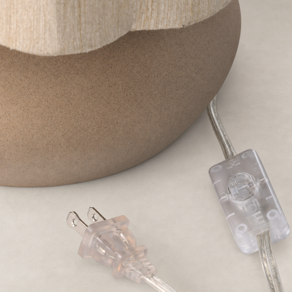 Tan speckled ceramic table lamp base with a clear power cord detail.
