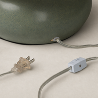 Matte sage ceramic table lamp showcasing a stylish power cord connection.