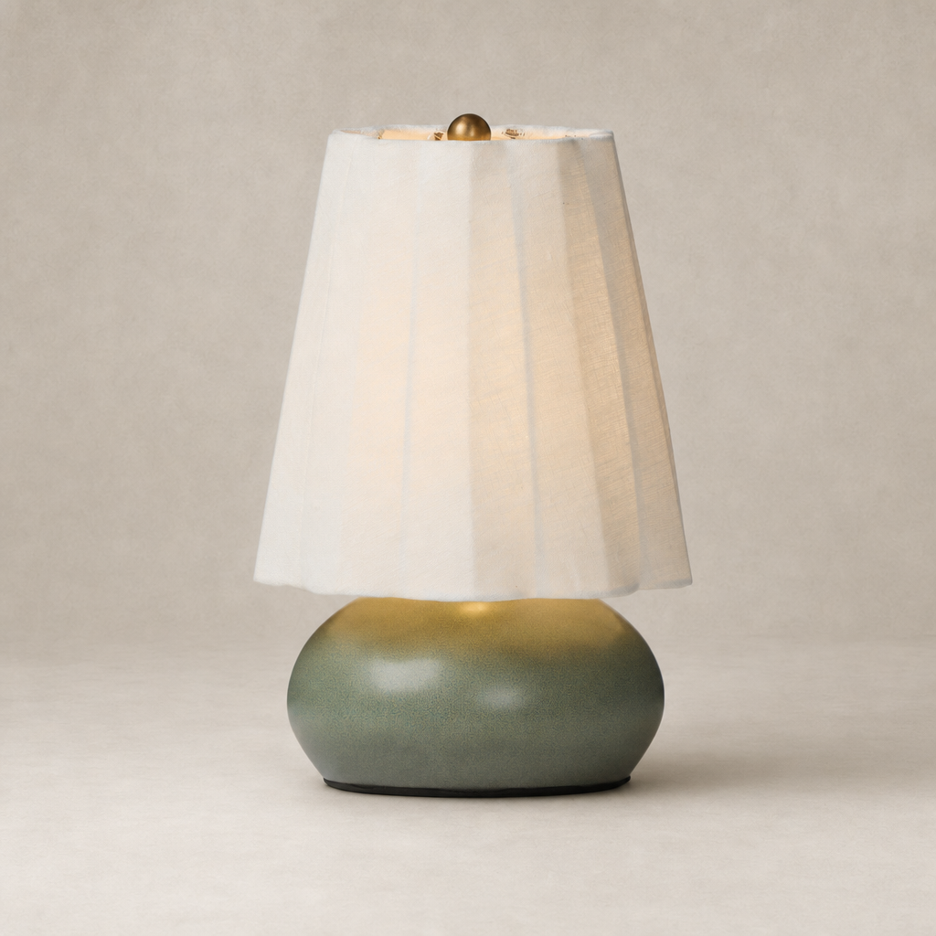 Matte sage ceramic table lamp with a textured round base and soft fabric shade.