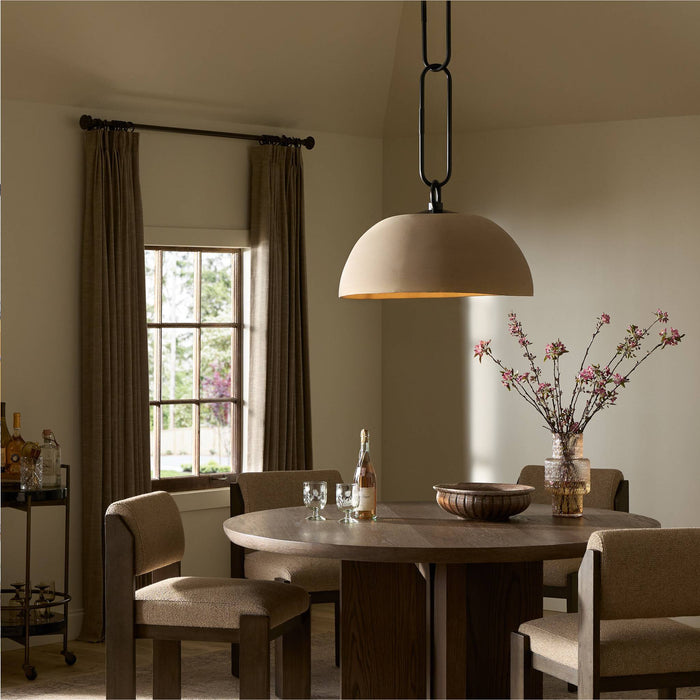 Tan speckled ceramic pendant light hanging above a round dining table in a cozy setting.