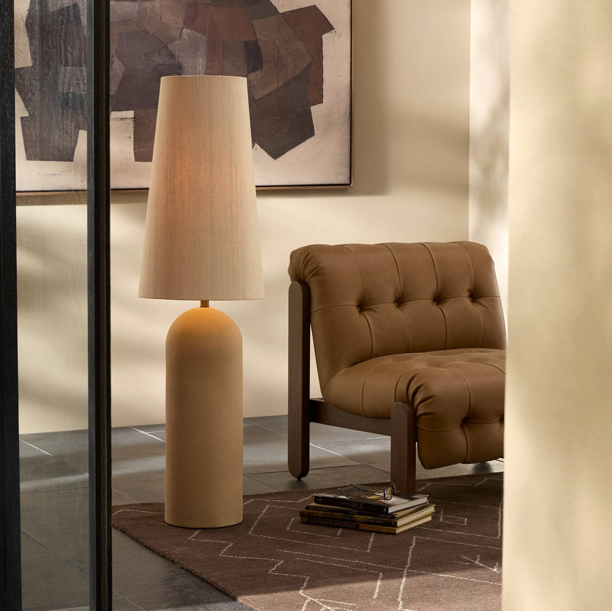 Tan speckled ceramic floor lamp with a tapered shade in a cozy living room setting.