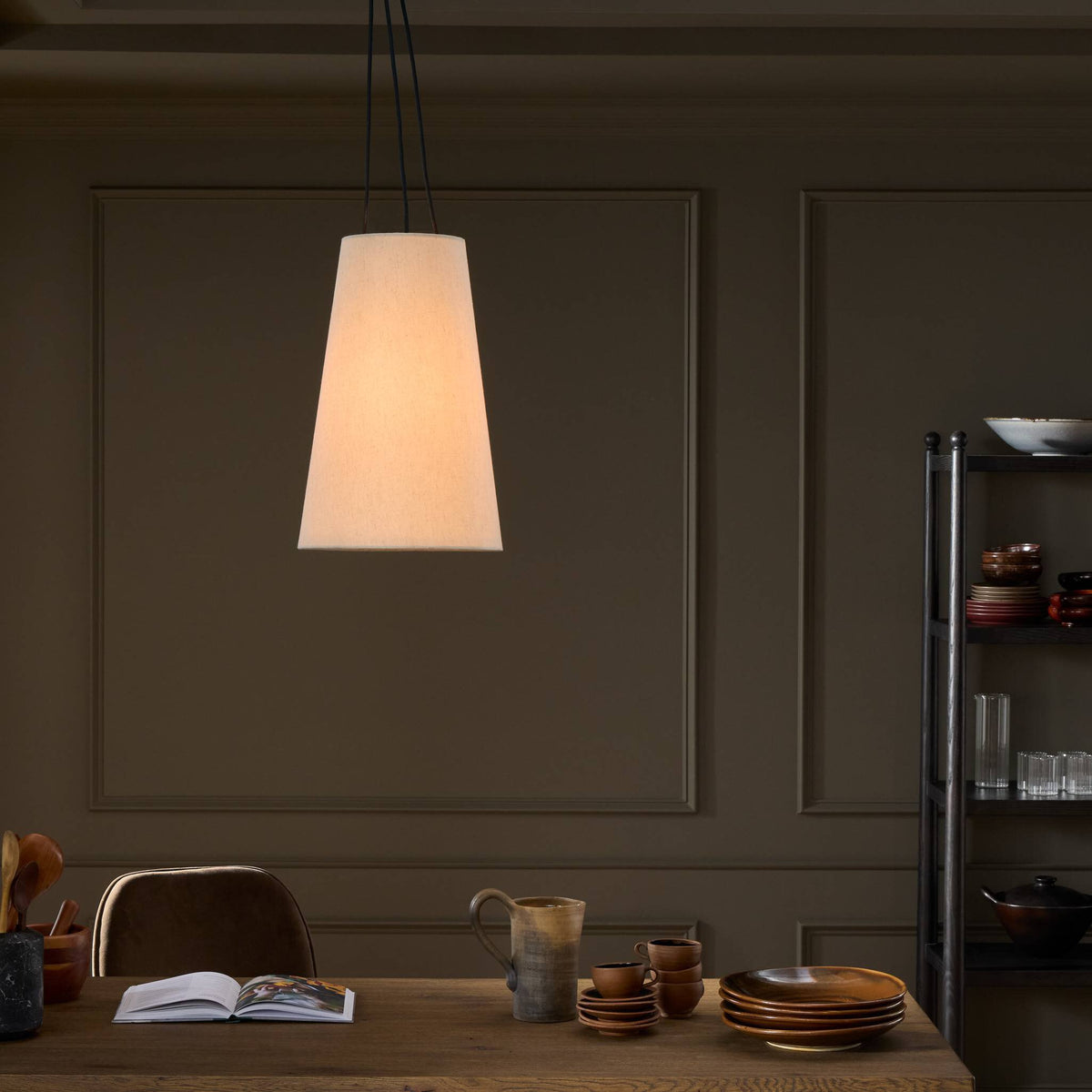 Jet Black pendant light hanging elegantly over a wooden dining table setting.