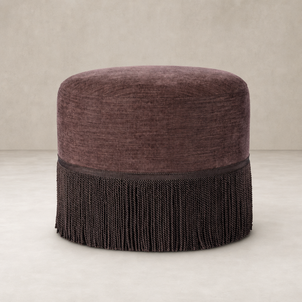 Round fringe ottoman in Laughlin Plum with textured fabric and elegant trim.