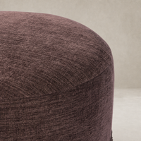 Round Fringe Ottoman in Laughlin Plum fabric with textured surface.