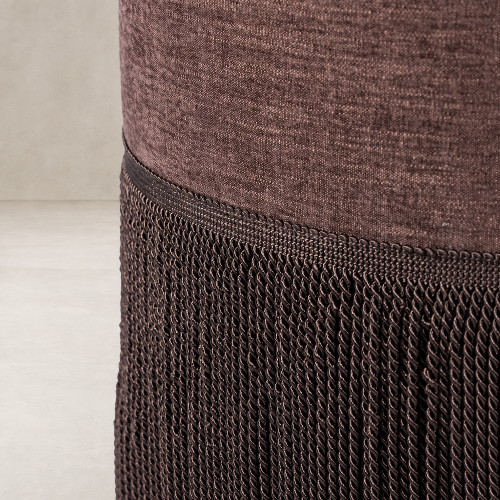 Fringe ottoman in Laughlin Plum with textured fabric and decorative fringe detail.