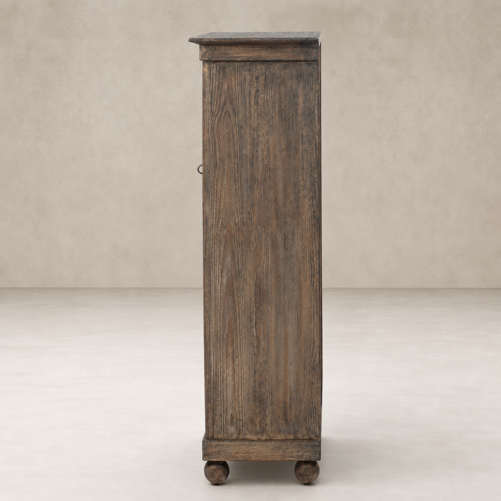 Lisbon Cabinet in distressed cocoa pine featuring a tall, narrow design with round wheels.