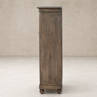 Lisbon Cabinet in distressed cocoa pine featuring a tall, narrow design with round wheels.