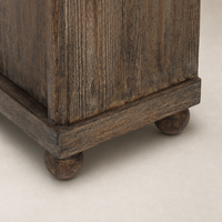 Distressed Cocoa Pine Lisbon Cabinet corner detail showcasing textured wood and rounded feet.