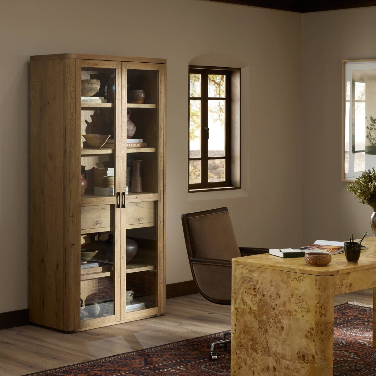 Side angle of the Arcadia Cabinet in a warm wood finish, displaying decorative items through glass doors.