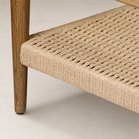Brandy Coffee Table features a woven natural fiber shelf and wooden legs.