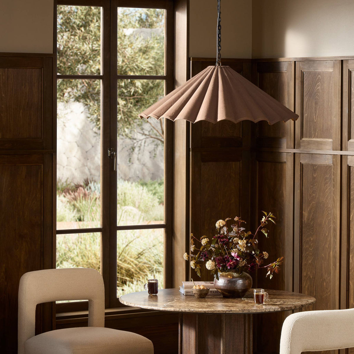 Espresso canvas pendant light with scalloped edges hanging over a rustic dining table.