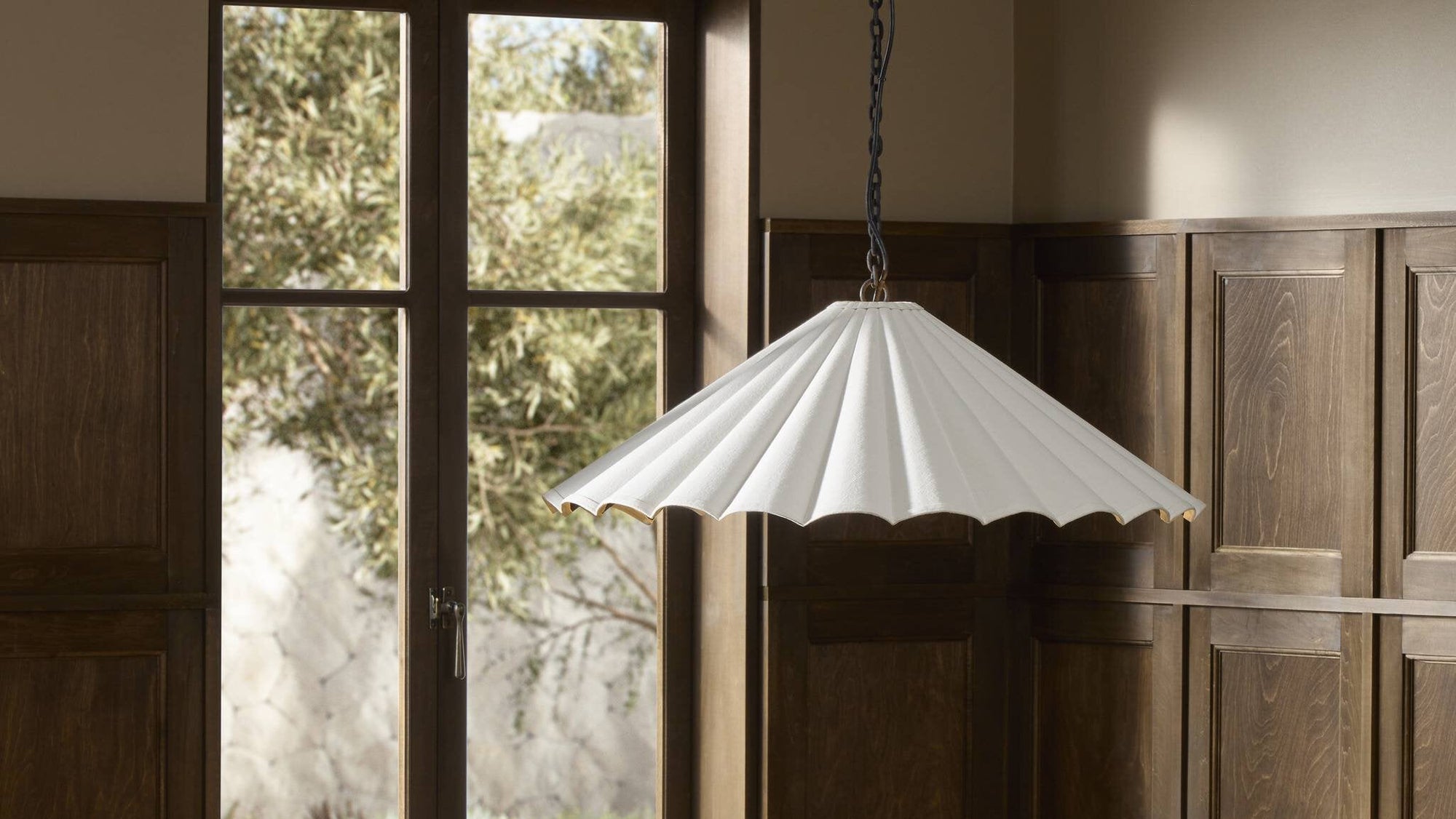 Cream canvas pendant light featuring a scalloped design, suspended above a dining table.