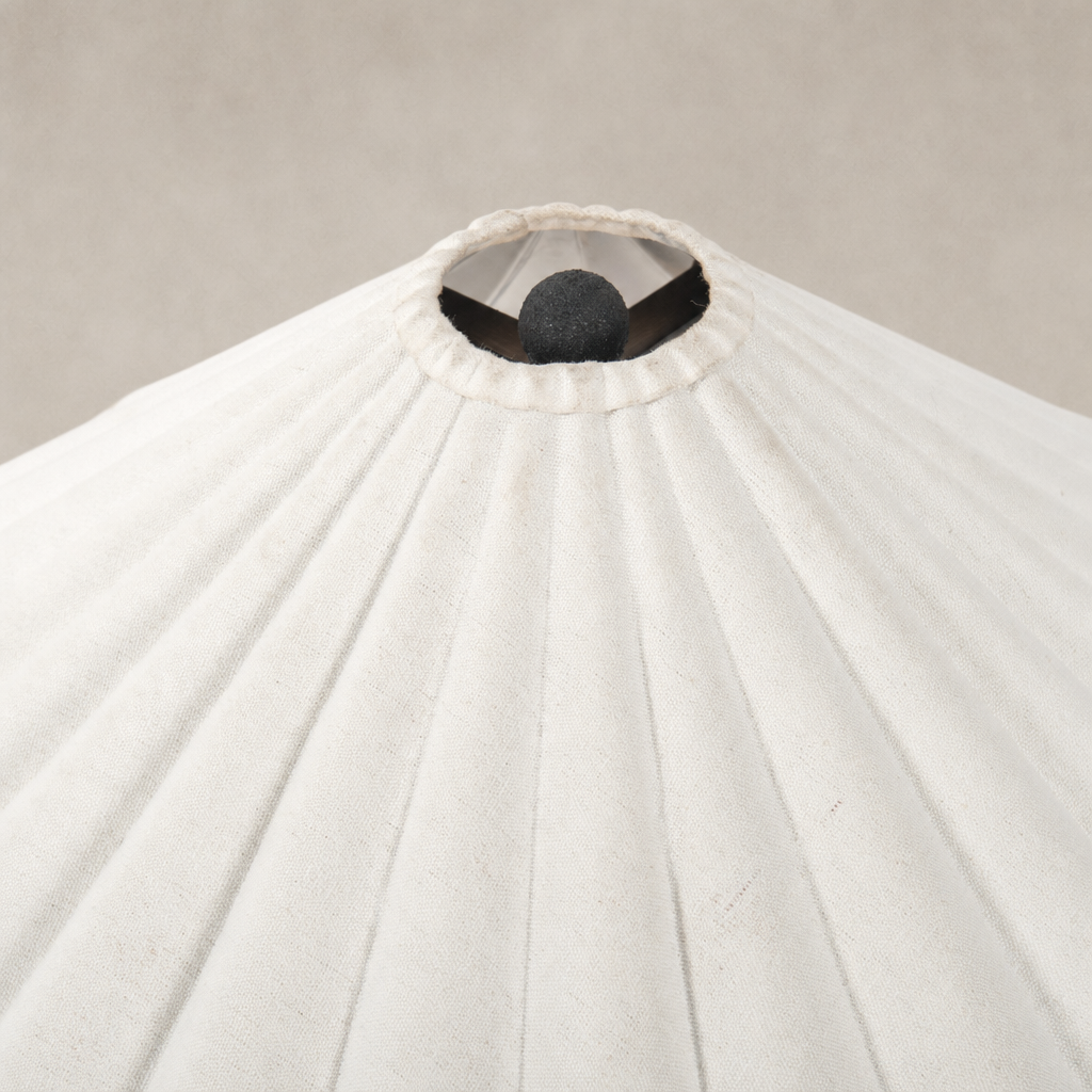 Cream canvas table lamp with pleated shade and central decorative sphere.