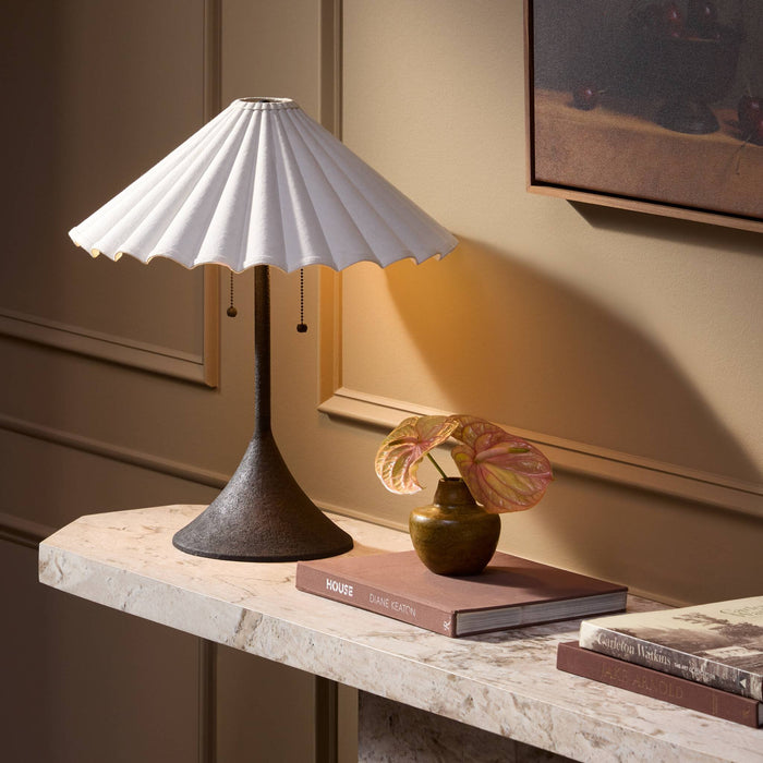Cream canvas table lamp with a textured shade and a sculptural metal base.
