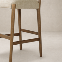 Kauri Bar + Counter Stool in Alcala Wheat features a textured fabric seat and sturdy wooden legs.