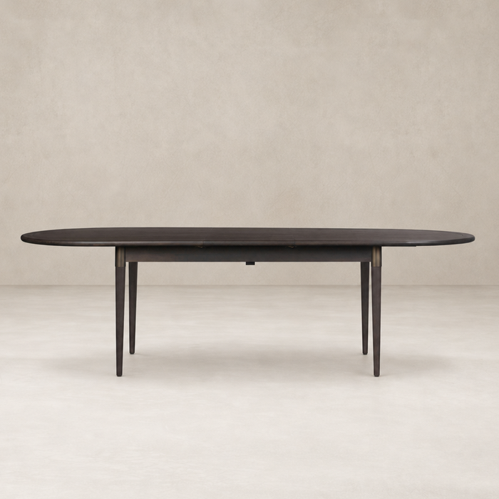 Cortina Oval Extension Dining Table in black mango with sleek, tapered legs and elegant design.