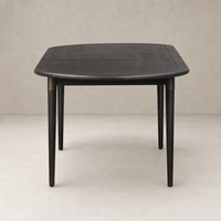 Cortina Oval Extension Dining Table in black mango, featuring smooth curves and tapered legs.