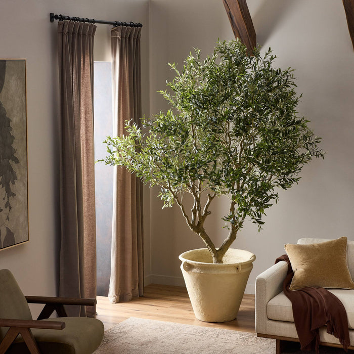 Lifelike Iris Olive Tree Wide in a textured cream pot, enhancing a cozy living room.