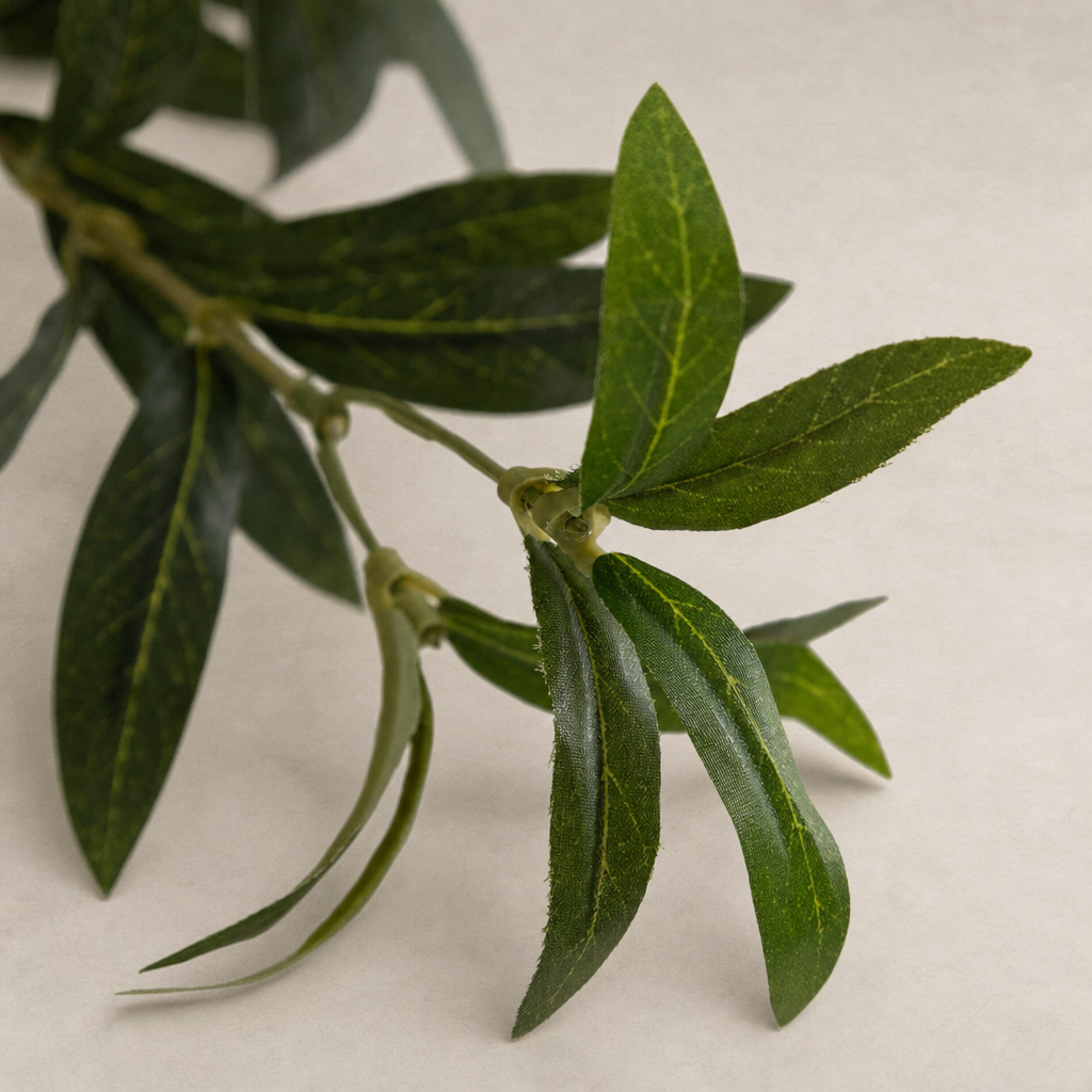 Close-up of faux olive tree wide leaves showcasing realistic texture and vibrant green hues.