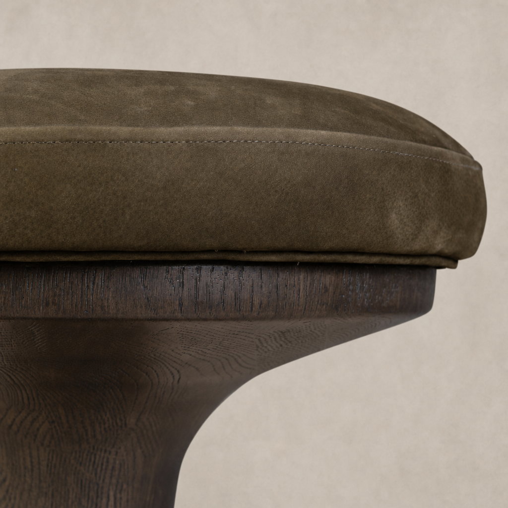 Nubuck olive counter stool with a curved wooden base and plush seat.