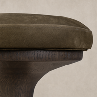 Nubuck olive counter stool with a curved wooden base and plush seat.