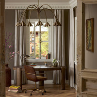 Aged antique brass iron chandelier with an elegant arc design in a stylish workspace.