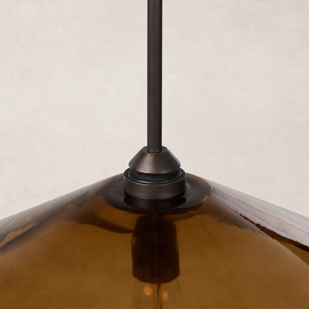 Amber glass pendant with a sleek metal fixture and elegant geometric shape.