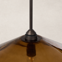Amber glass pendant with a sleek metal fixture and elegant geometric shape.