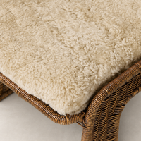 Beige shorn shearling cushion on the Ingrid Dining Chair's woven base.