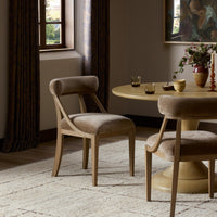 Stylish dining chair in Altair Mushroom upholstery next to a round wooden table.