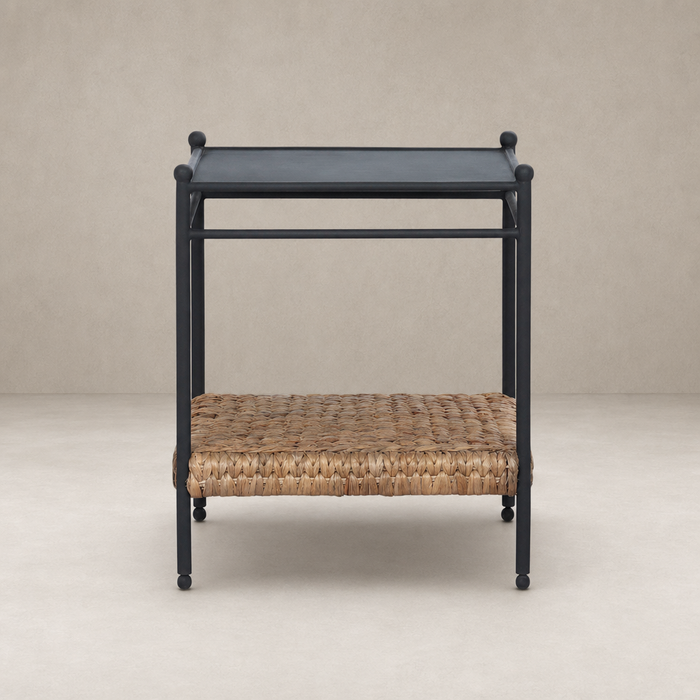 Colette End Table with a sleek black frame and woven natural fiber shelf.